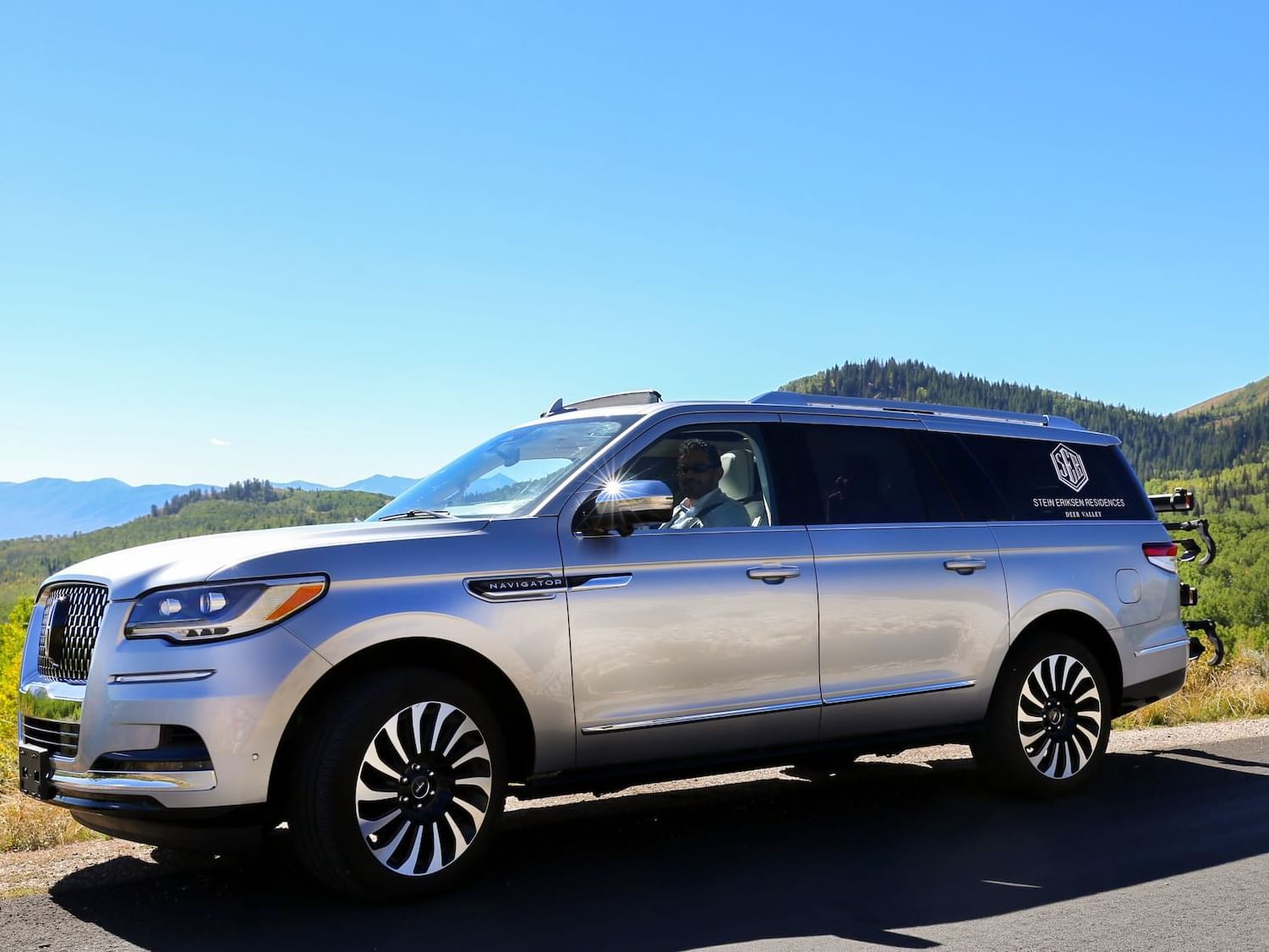 A vehicle on road with mountain view behind near The Chateaux Deer Valley