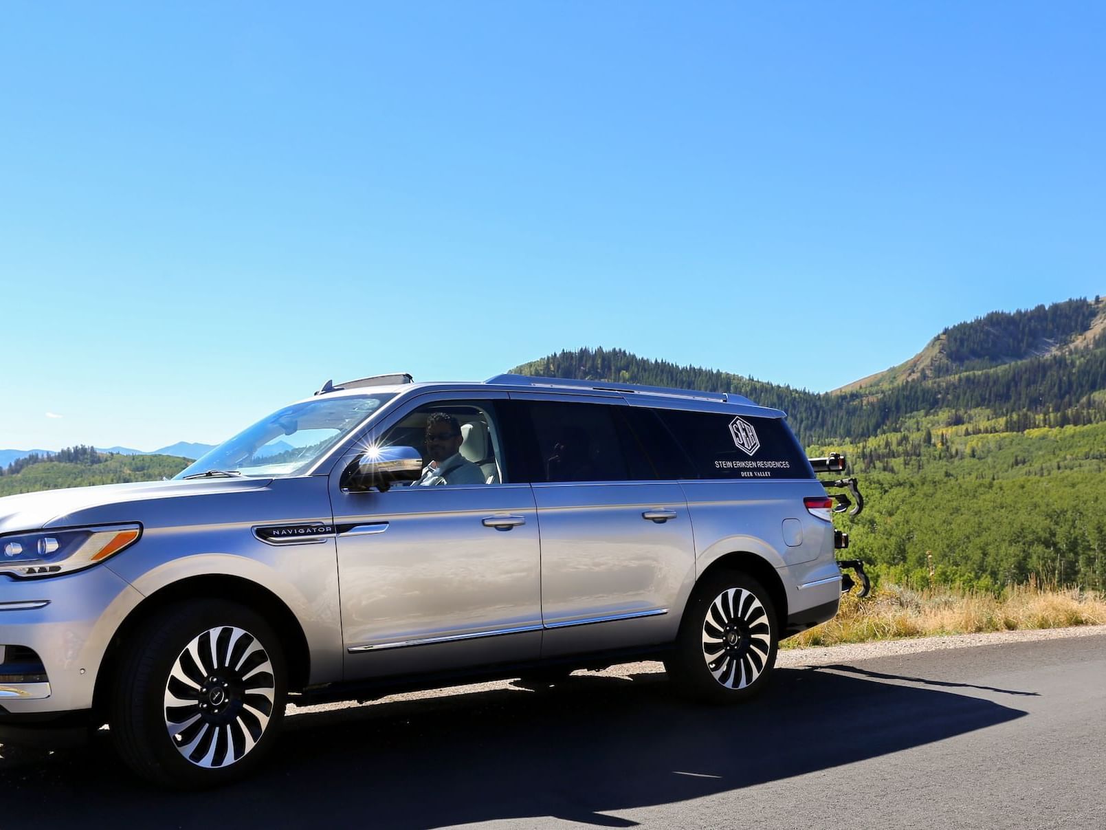 A vehicle on road with mountain view behind near The Chateaux Deer Valley