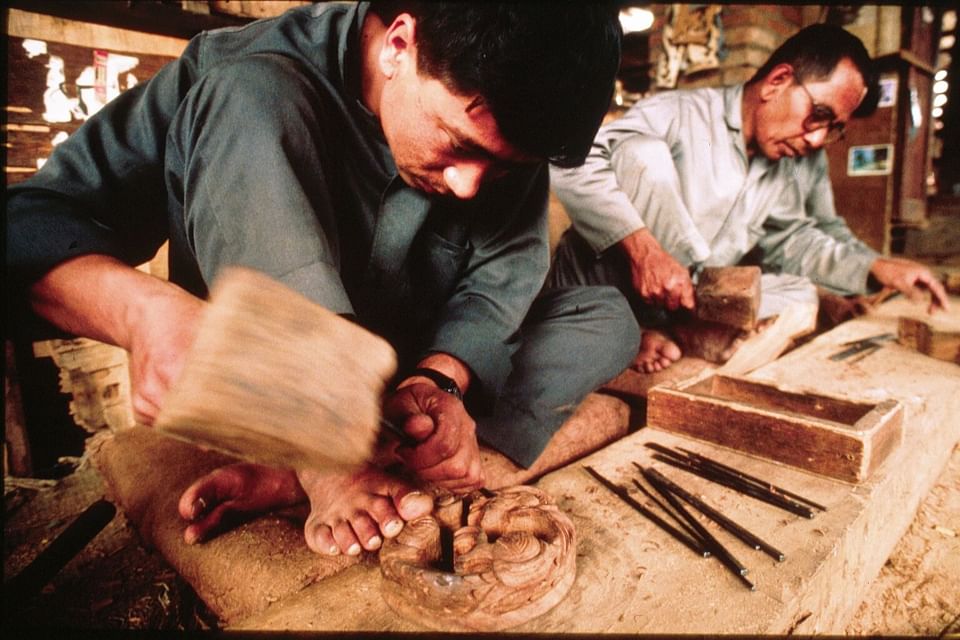 Carpenters working on a table with tools and materials spread out in front of them near Dwarika's Hotel Kathmandu