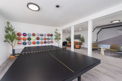 Black ping pong table and wall of colorful basketballs in the lounge at The Varsity South