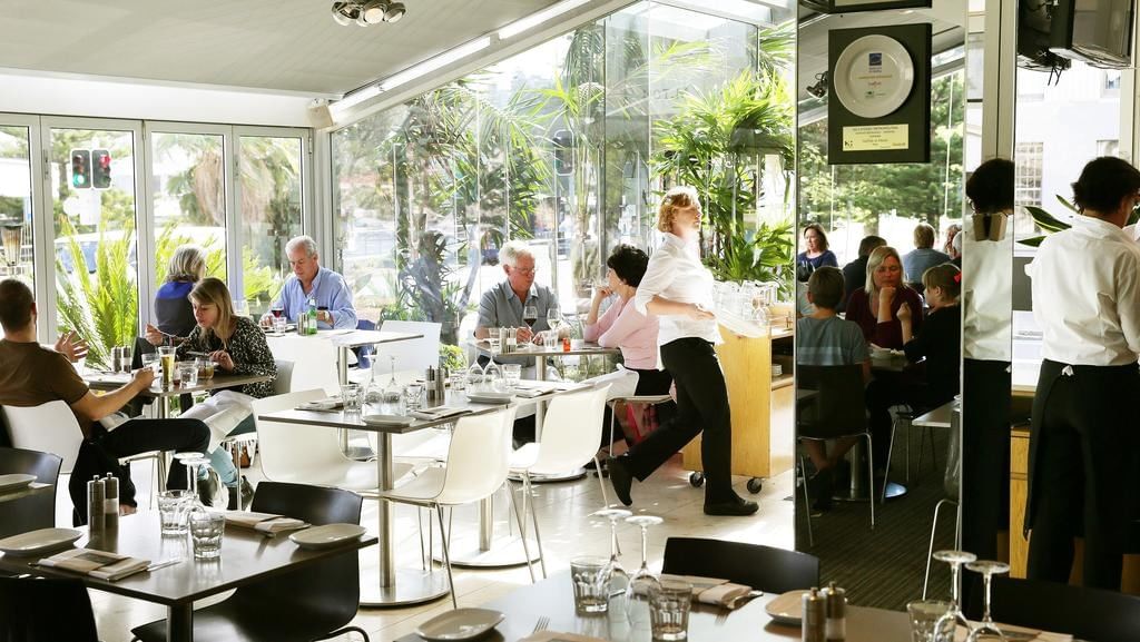 Garfish Restaurant & Bar at Elysium Hotels with floor-to-ceiling windows overlooking greenery and seated with coustomers