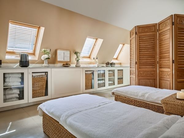 Spa treatment area, with massage tables by white cabinets, under a sloped wooden ceiling at Hotel Westminster Paris