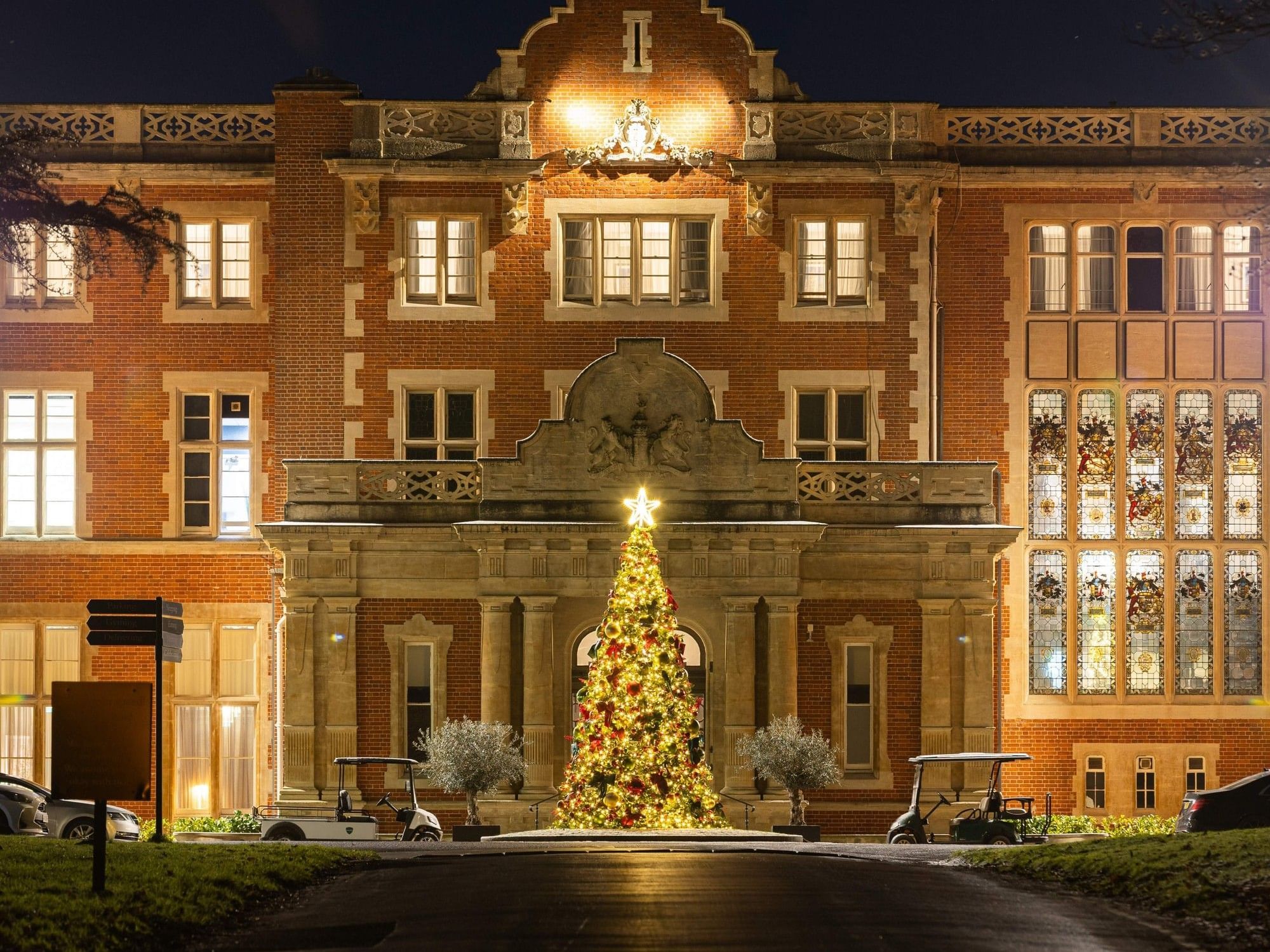 Illuminated Victorian mansion with festive Christmas tree at entrance at Easthampstead Park Hotel in Bracknell
