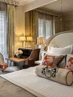 Elegant Superior Double Room with large bed, floral pillows, and ornate desk at Hotel Westminster Paris
