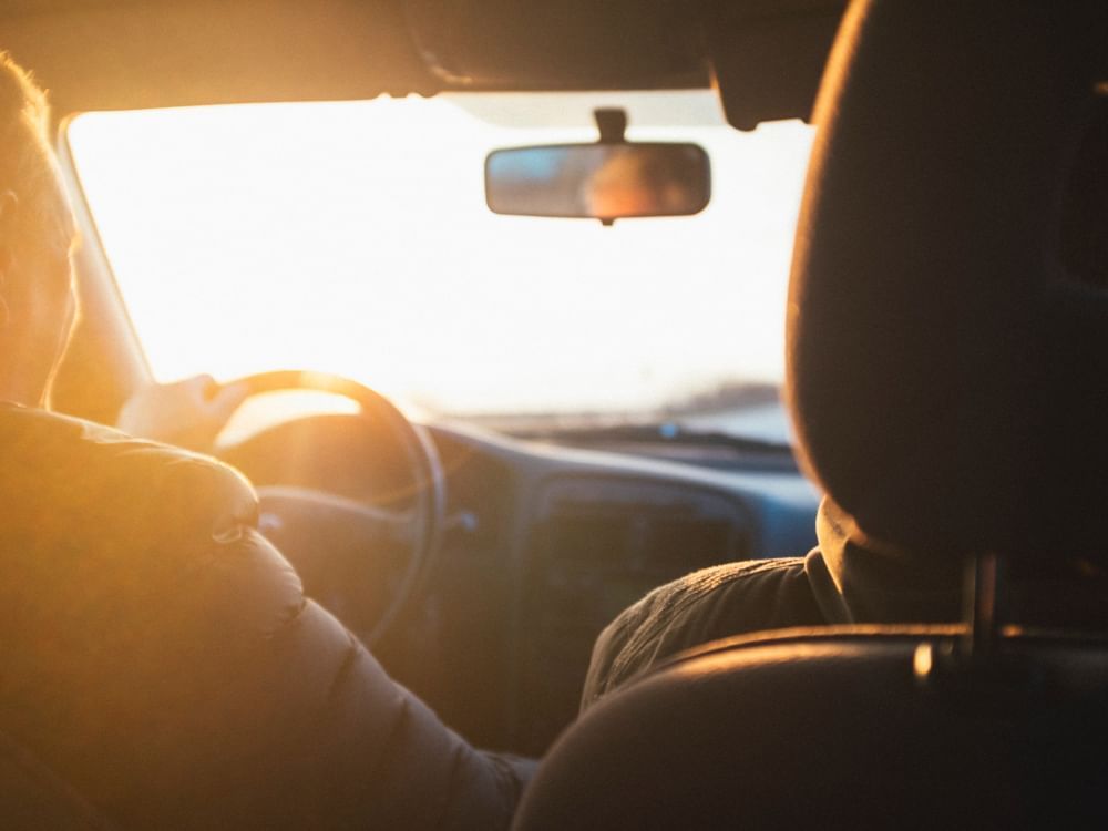 man happily driving his car with the sun in his eyes