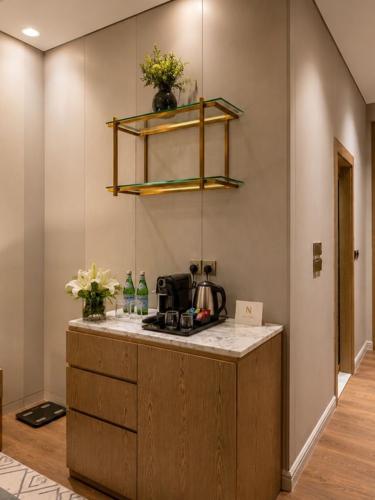 Entry hallway with wooden refreshment cabinet and bedside nightstand in Deluxe Room at Naviti by Warwick Jeddah