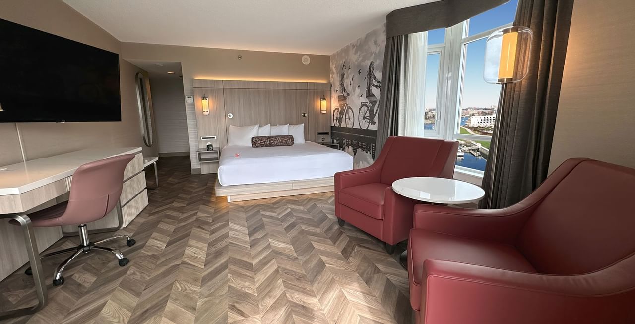 Hotel guestroom with King bed, TV, work desk, two sofas, and a window