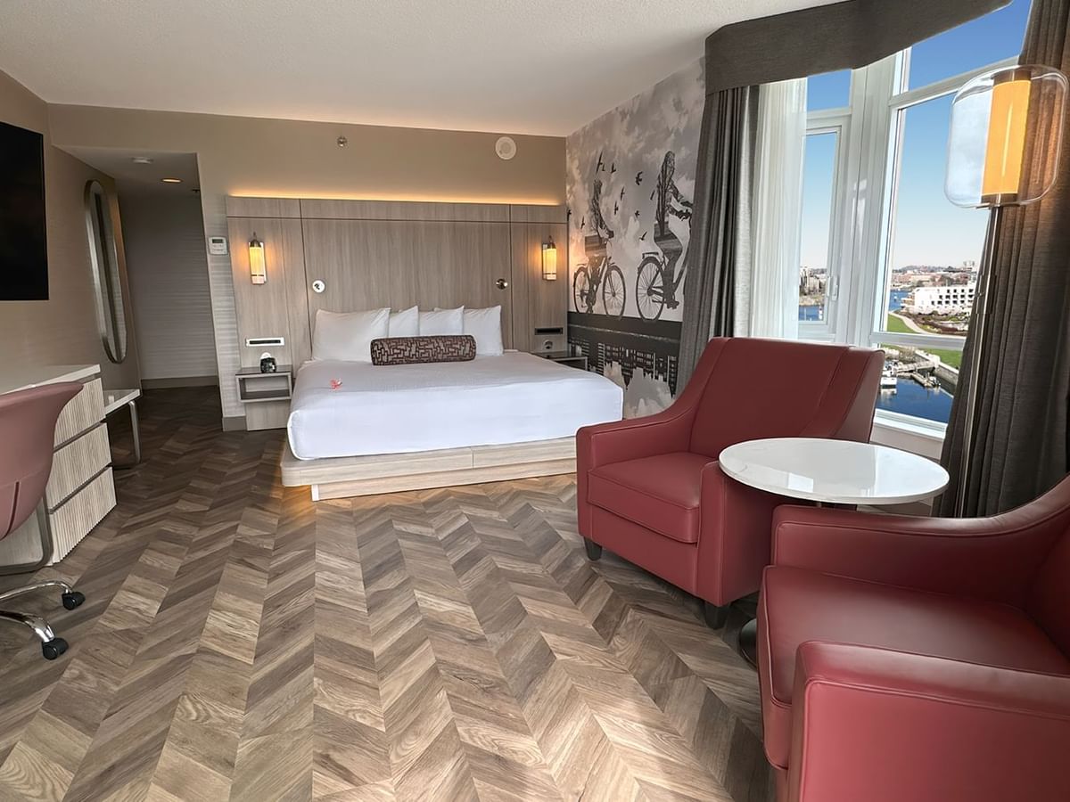 Hotel guestroom with bed, window, TV, work desk, and two sofas.