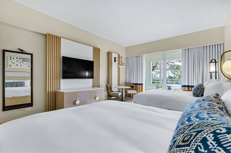 Small dining table and TV facing the cozy beds in Las Vistas Garden View 2-Queen Room at El Conquistador Resort