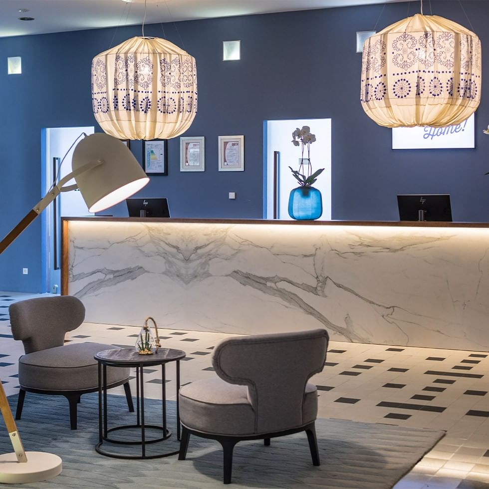 Reception area with marble counter, two chairs, side table, and decorative lanterns hanging from the ceiling.