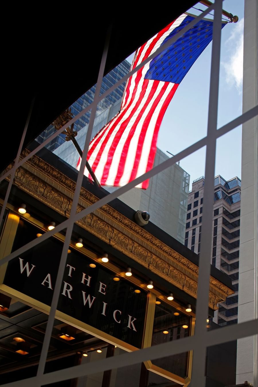 View of the American flag waving above the ornate gold trim of the Warwick New York