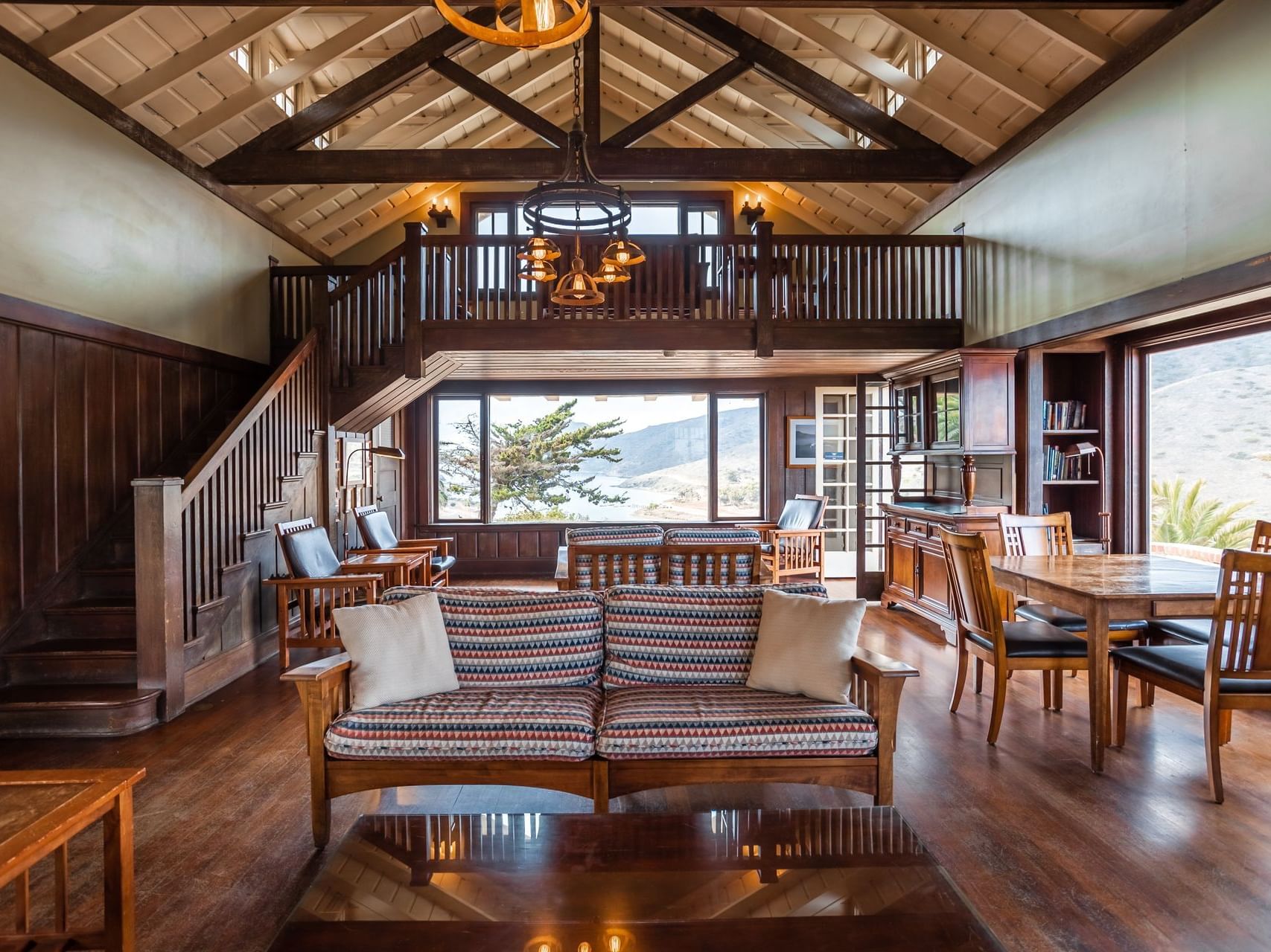 Living room area with seatings and staircase at Banning House Lodge, on of the catalina island california vacation packages