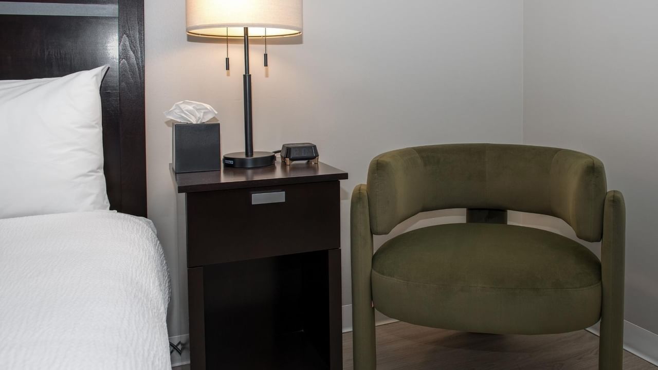 Guest room seating area at Coast Innisfail Hotel with armchair and bedside table
