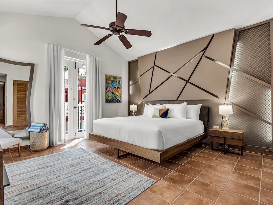 Cama con cabecera de diseño geométrico junto a la gran ventana en la One Bedroom Garden Villa Accessible en Las Casitas Village.
