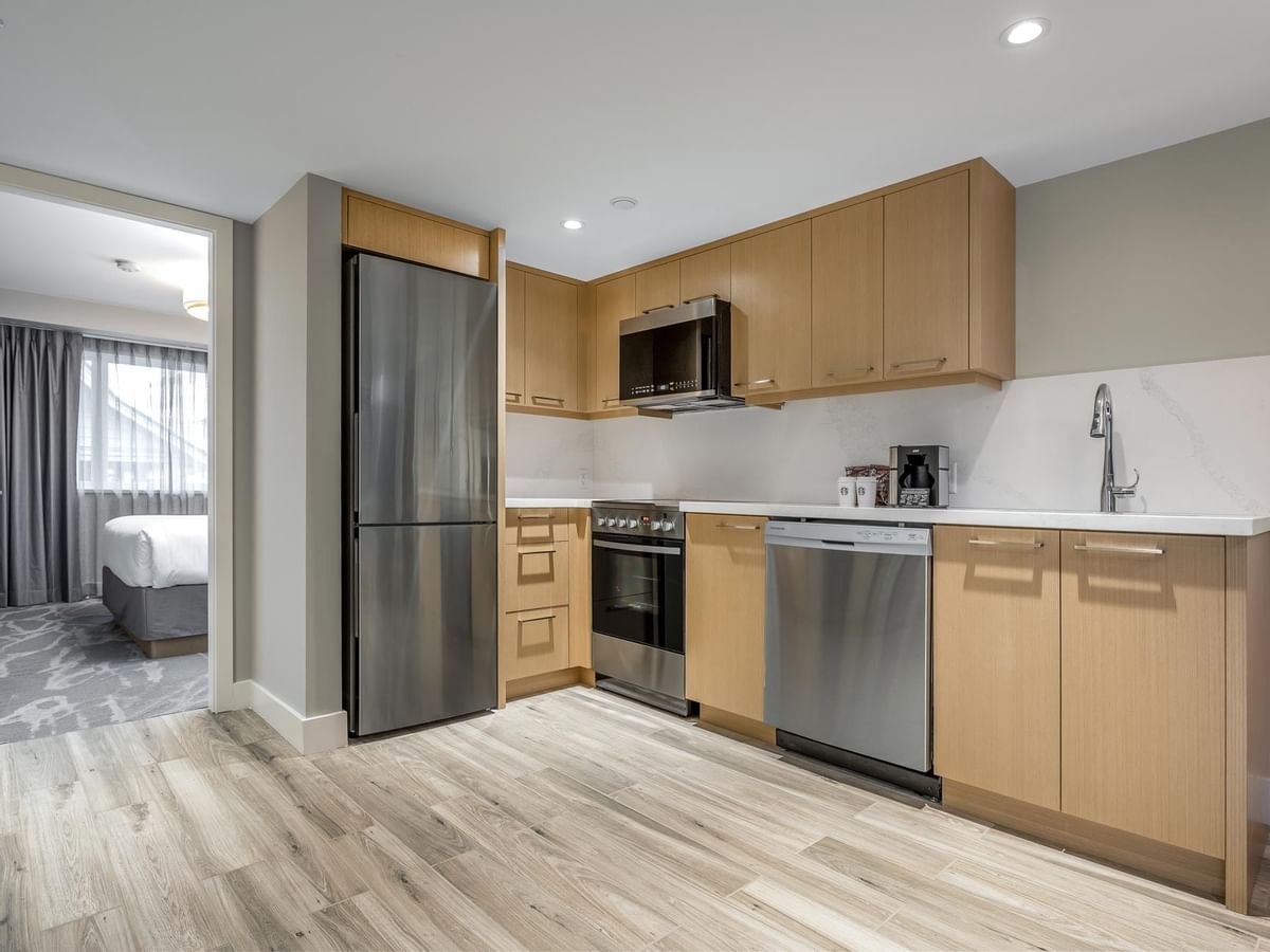 View of the full kitchen with oven, microwave, fridge, dishwasher and sink, with a view into the second bedroom