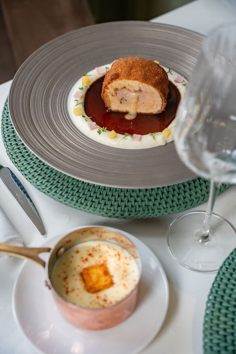 Meat dish with creamy sauce served on a textured plate by a wine glass at Hotel Westminster Paris