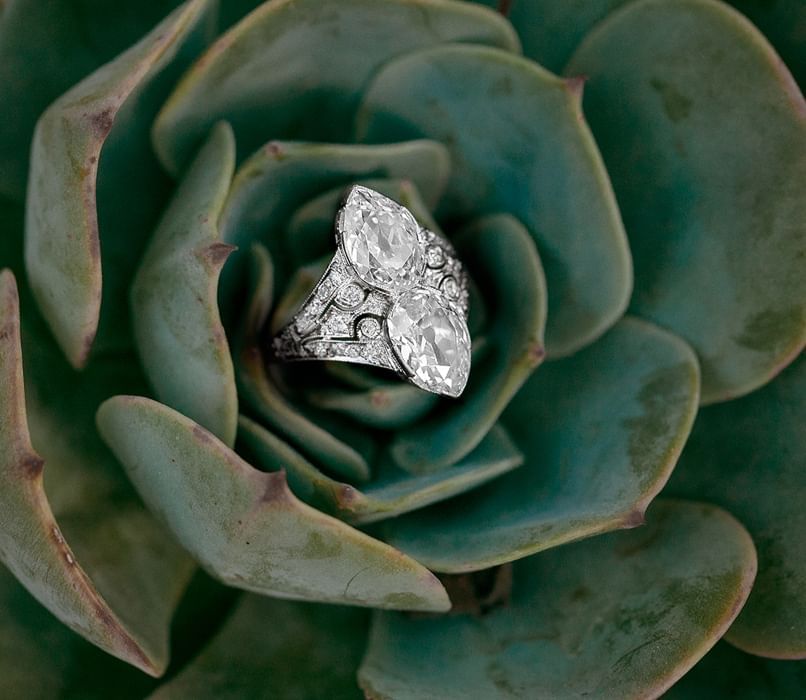 A silver ring with diamonds inside a green flower 