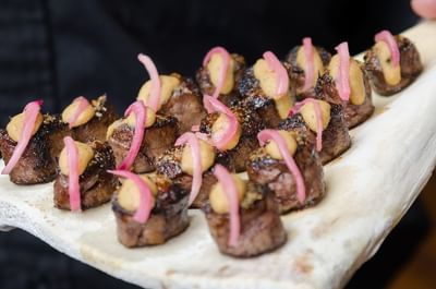 Seared meat topped with a dollop of a creamy sauce and garnished with thinly sliced red onions, served at The Stanley Hotel