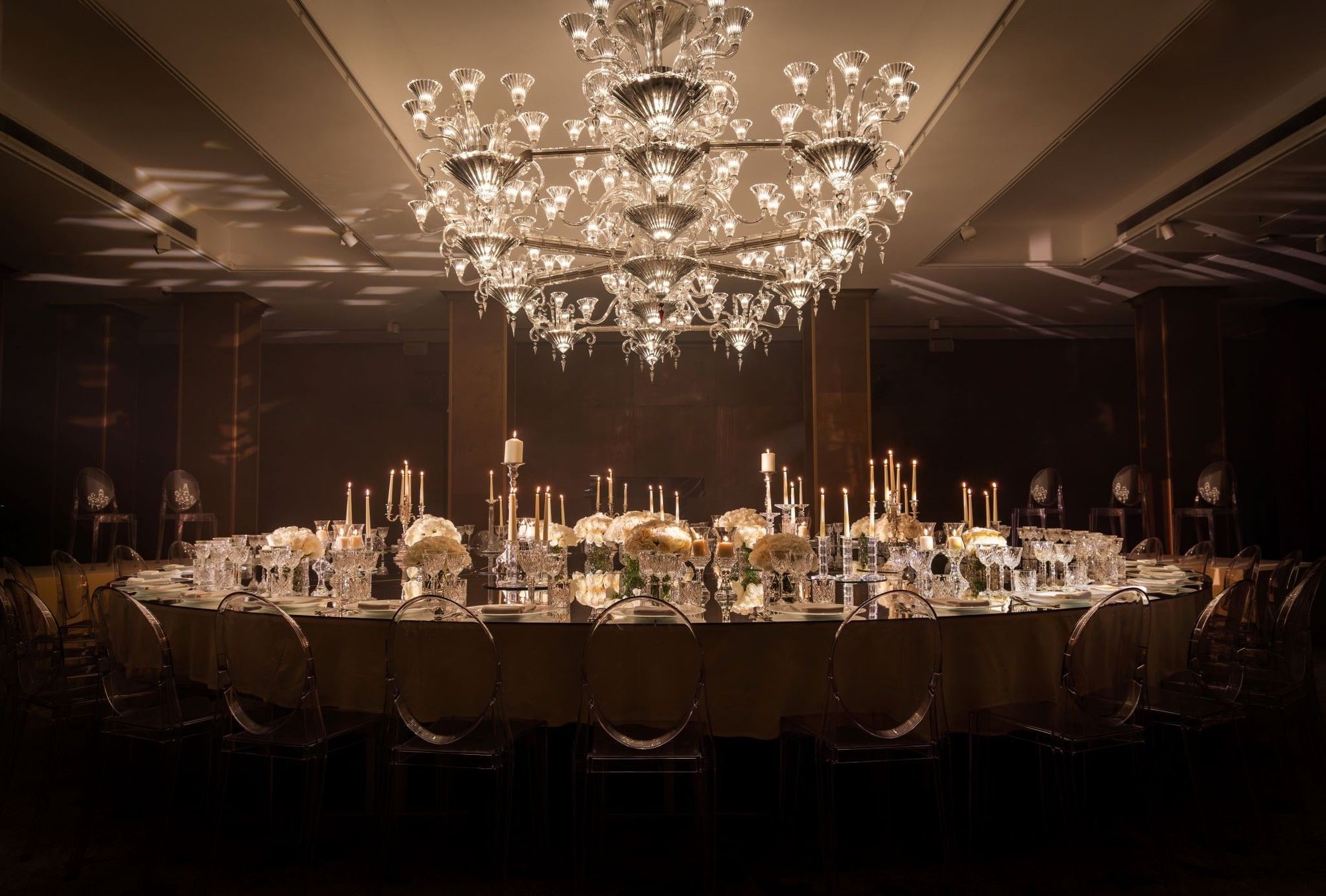 Chandelier above a banquet table set with flowers, candles, and glassware at The May Fair Hotel