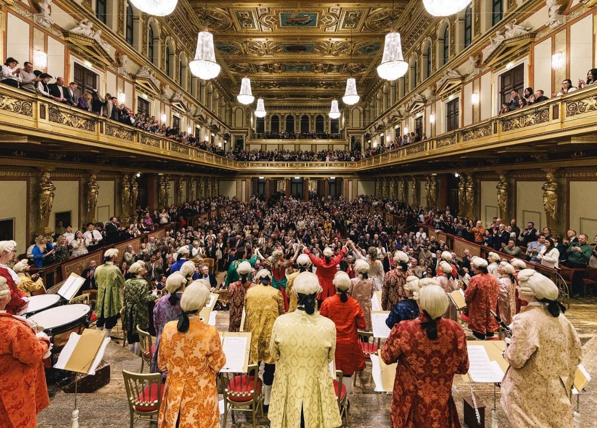 Musicians in historical costumes perform a Mozart concert in the opulent Golden Hall of the Vienna Musikverein in front of a full audience.