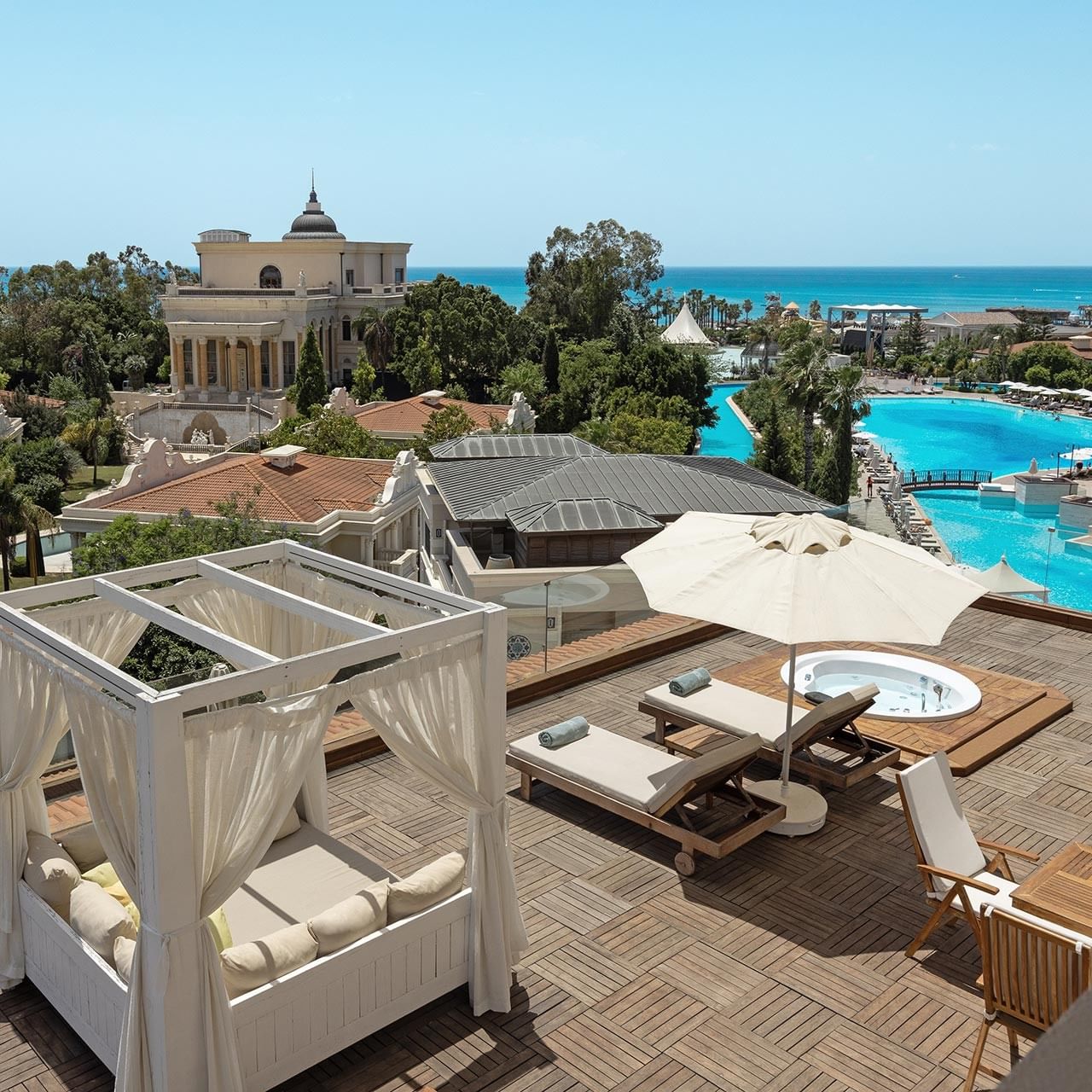 Терраса королевского двухуровневого люкса с видом на море, шезлонгами, зонтиками и спа-джакузи на фоне