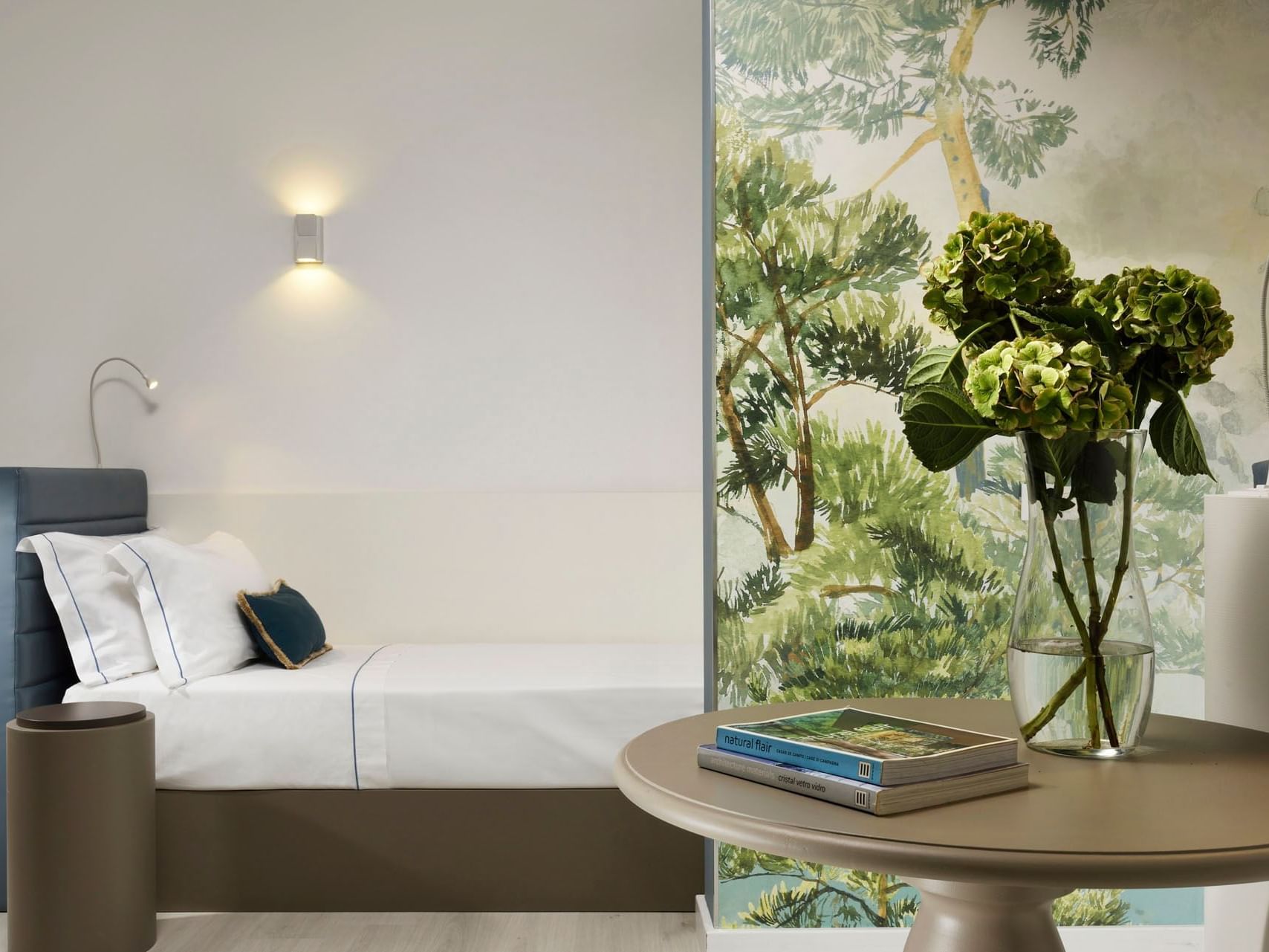 Bed & table with a forest wallpaper in Deluxe Triple Sea View at Golf Hotel Punta Ala