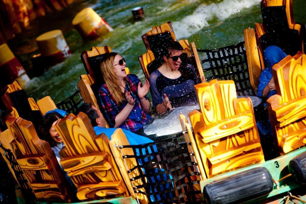 A round raft of people getting sprayed on a rapids ride.