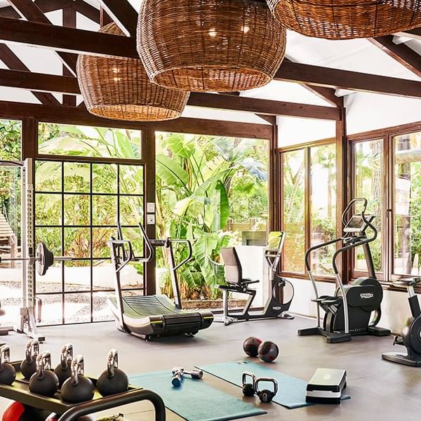 Fully equipped gym with cardio machines and kettlebells beneath woven pendant lights at the Marbella Club