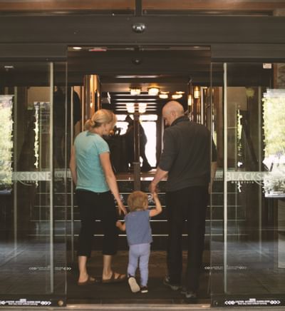 Couple holding a child, entering Blackstone Mountain Lodge with a warmly lit entrance