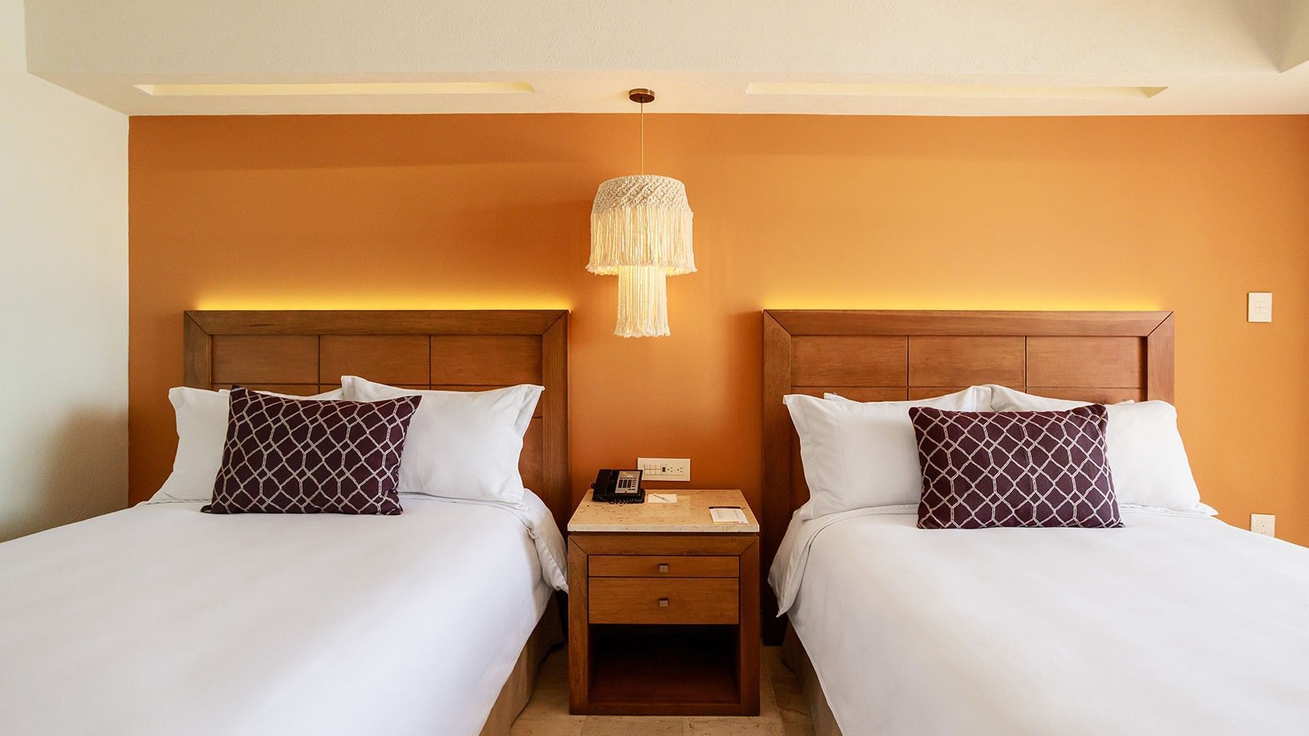 Symmetrical view of two queen beds in 2 Double Deluxe Superior with an orange wall at Camino Real Veracruz