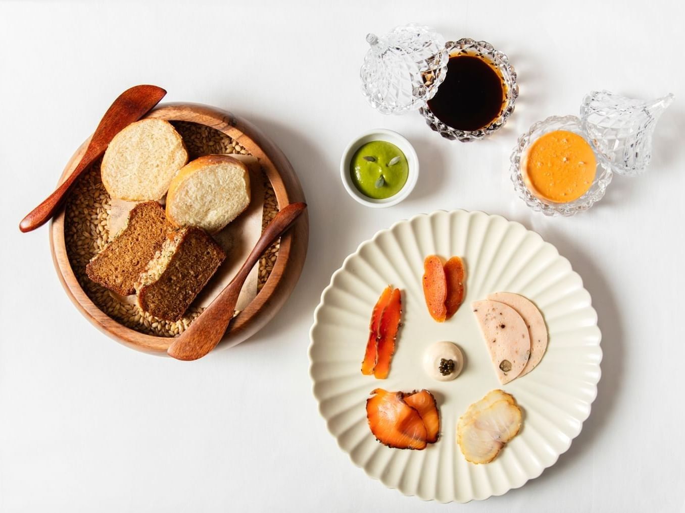 Artisanal bread bowl beside cured fish platter with dipping sauces on white background in Tom Brown at The Capital