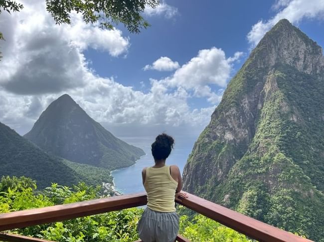 women on a wooden balcony at a St. Lucia resort, gazing at the stunning view of the Pitons