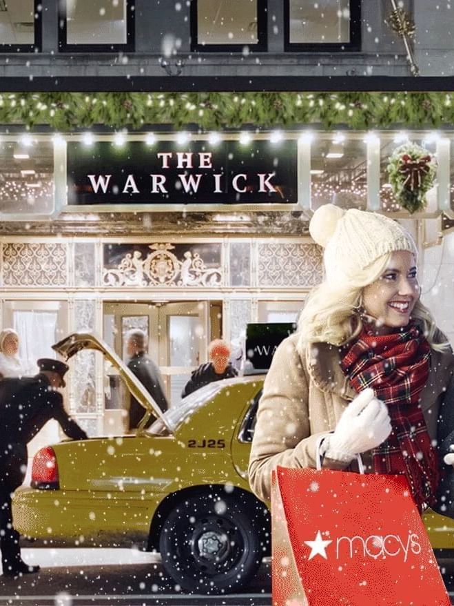 Happy couple walks past The Warwick hotel in the snow with Macy's shopping bags in front of Warwick New York 