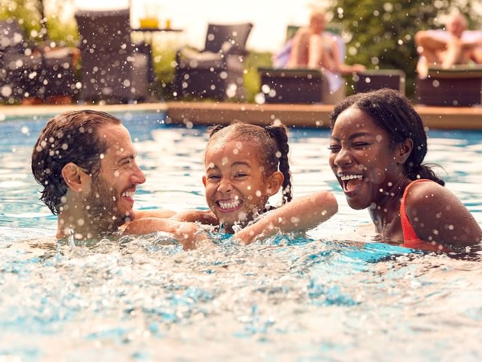 Happy family playing in an outdoor pool on a sunny summer day