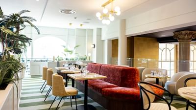 An elegant restaurant interior with striped flooring, modern furniture, and a chandelier above tables.