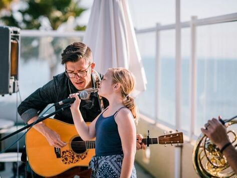 Guitarist playing guitar & singing next to a young girl on stage at SeaCrest Oceanfront Hotel Pismo Beach
