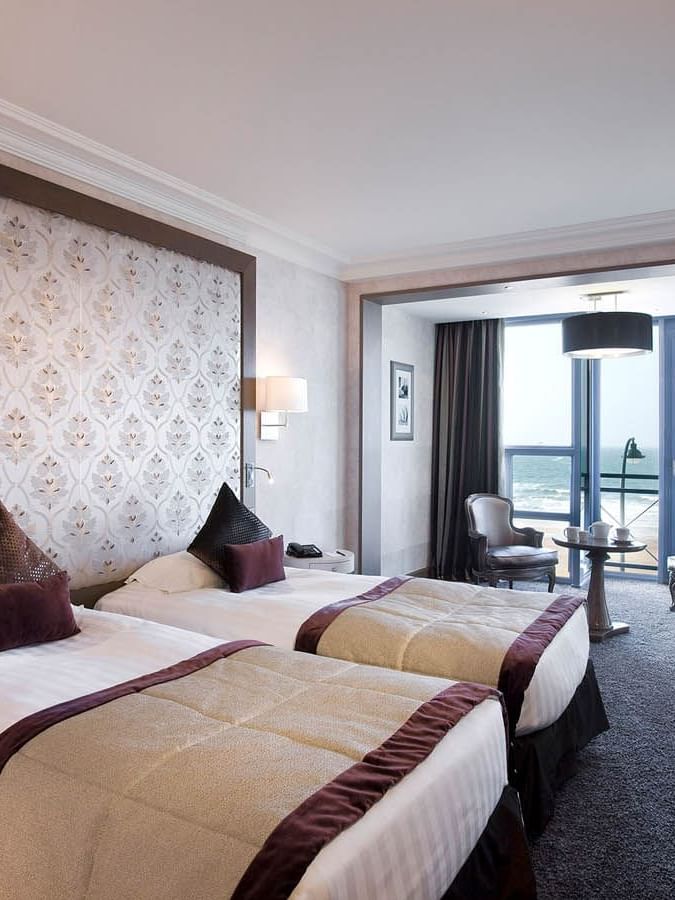Twin beds and small dining area in the Croisiere Prestige Room with a Sea view at Le Grand Hôtel des Thermes