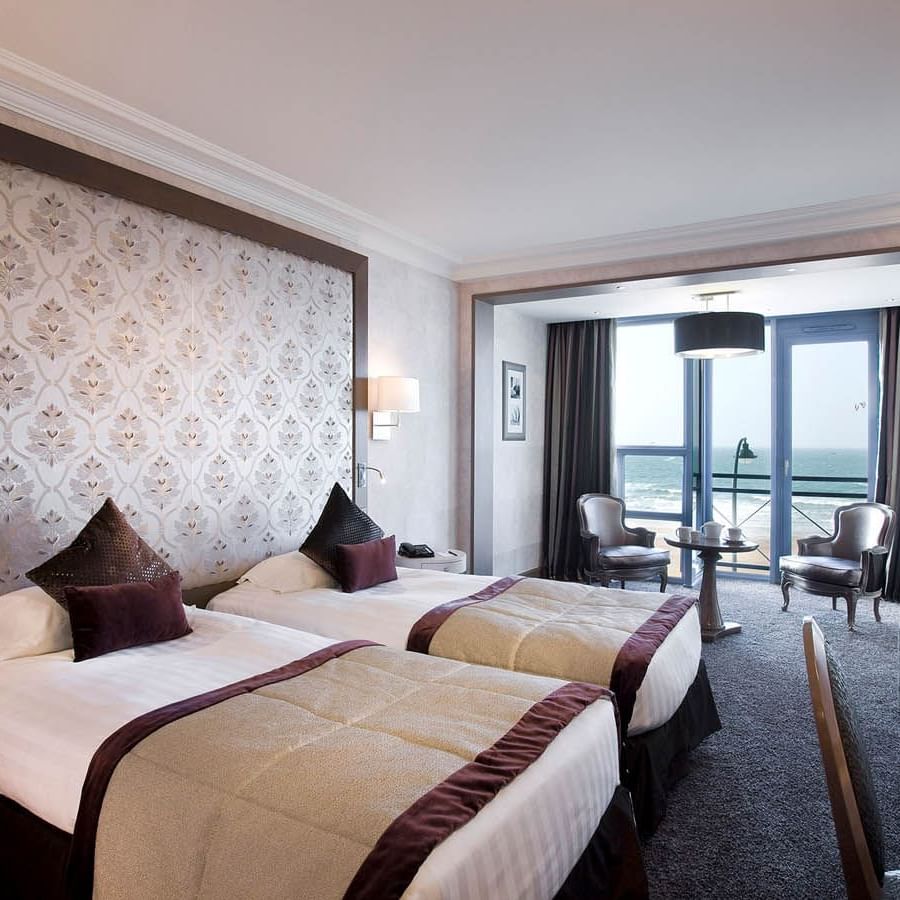 Twin beds and small dining area in the Croisiere Prestige Room with a Sea view at Le Grand Hôtel des Thermes