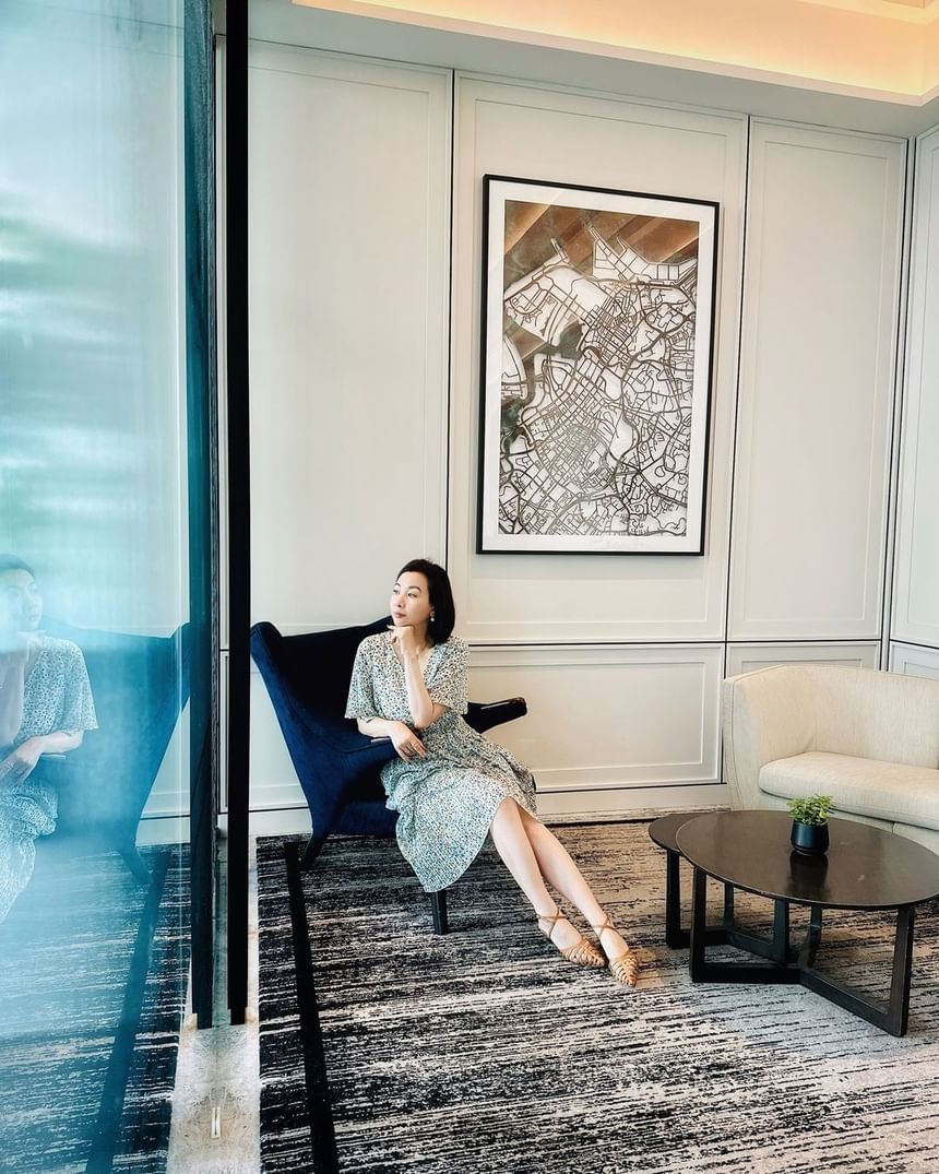 Lady sitting on a navy chair in a stylish room with framed artwork on the wall at Park Hotel Group