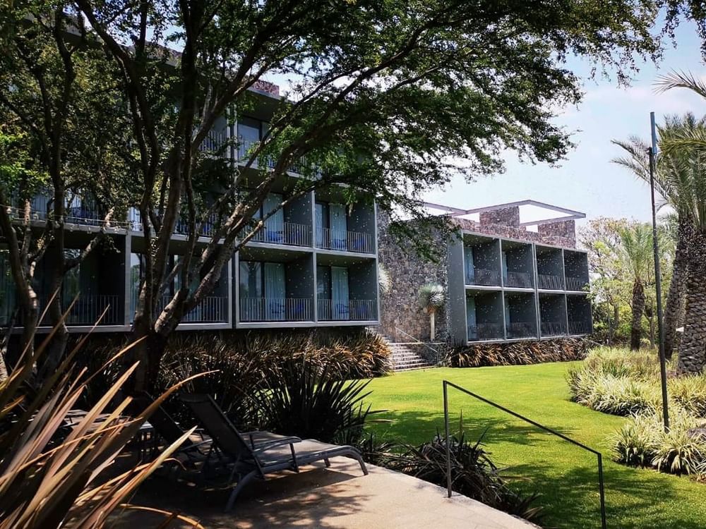 Hotel exterior with front garden and lounge chairs at Huayacán Cuernavaca Curamoria Collection