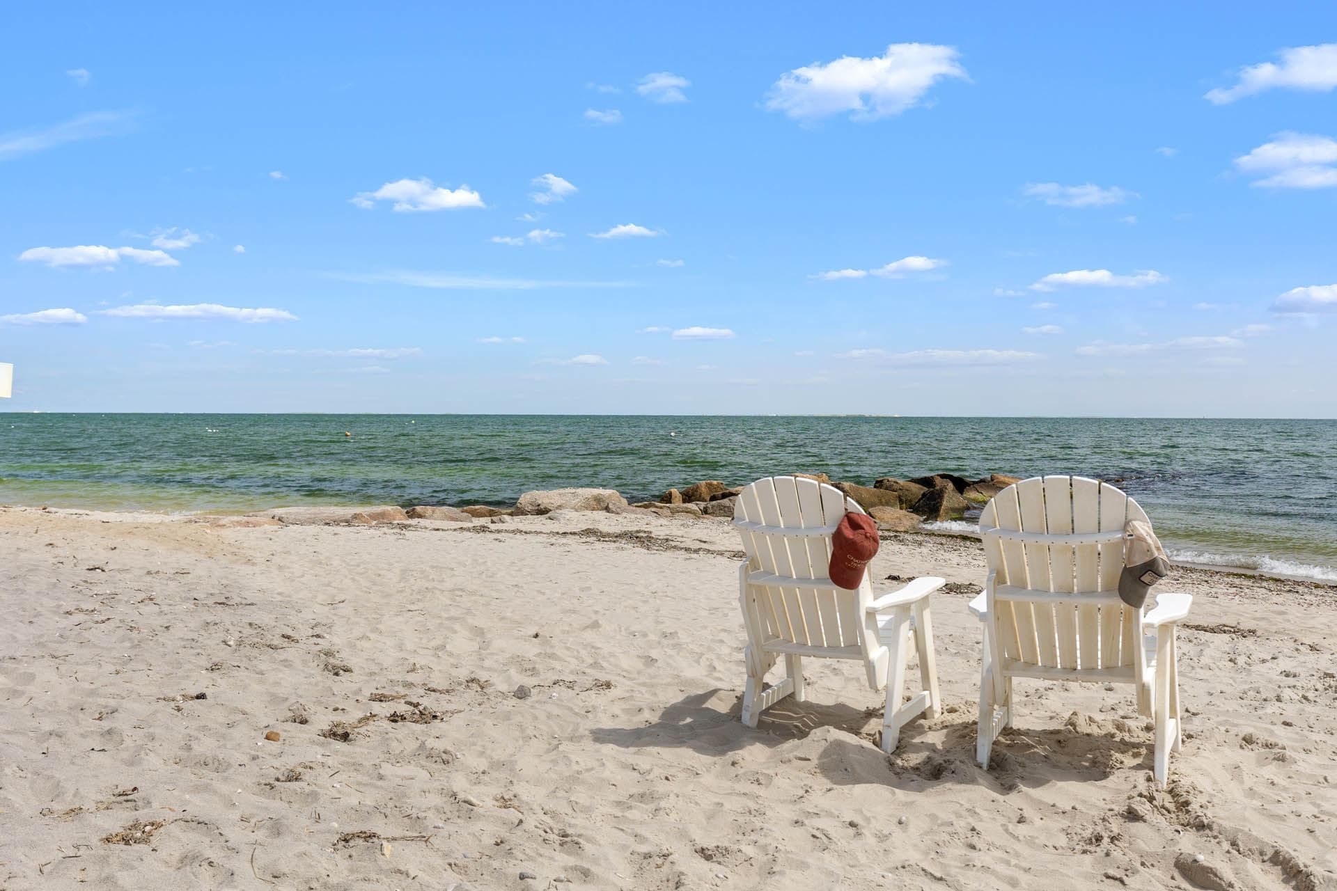 White wooden sun loungers towards the sea with hanging caps near Chatham Tides Resort