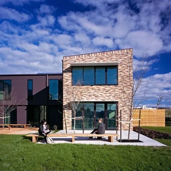 Modern brick building with two people sitting on a bench at La Trobe University - McFarlane's Hill Residences.