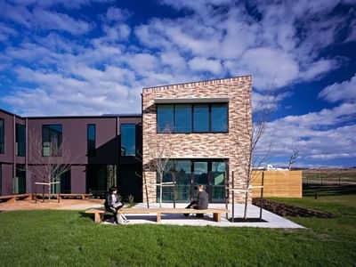 Modern brick building with two people sitting on a bench at La Trobe University - McFarlane's Hill Residences.