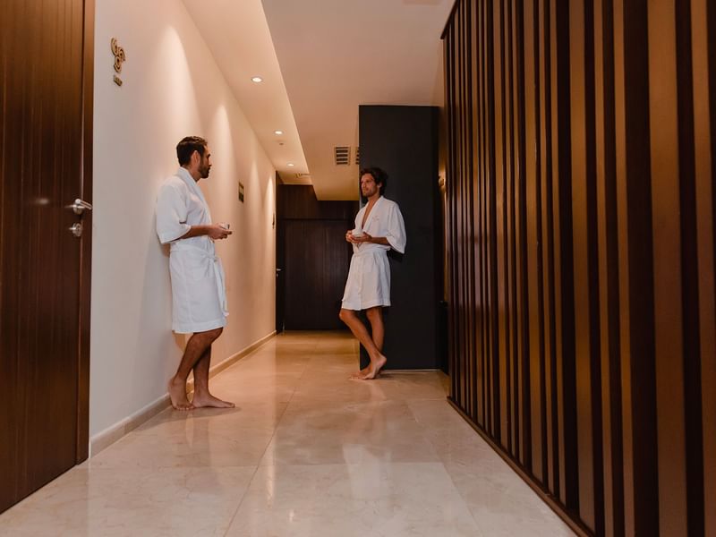 Two men in bathrobes chatting at Okom spa in The Reef 28