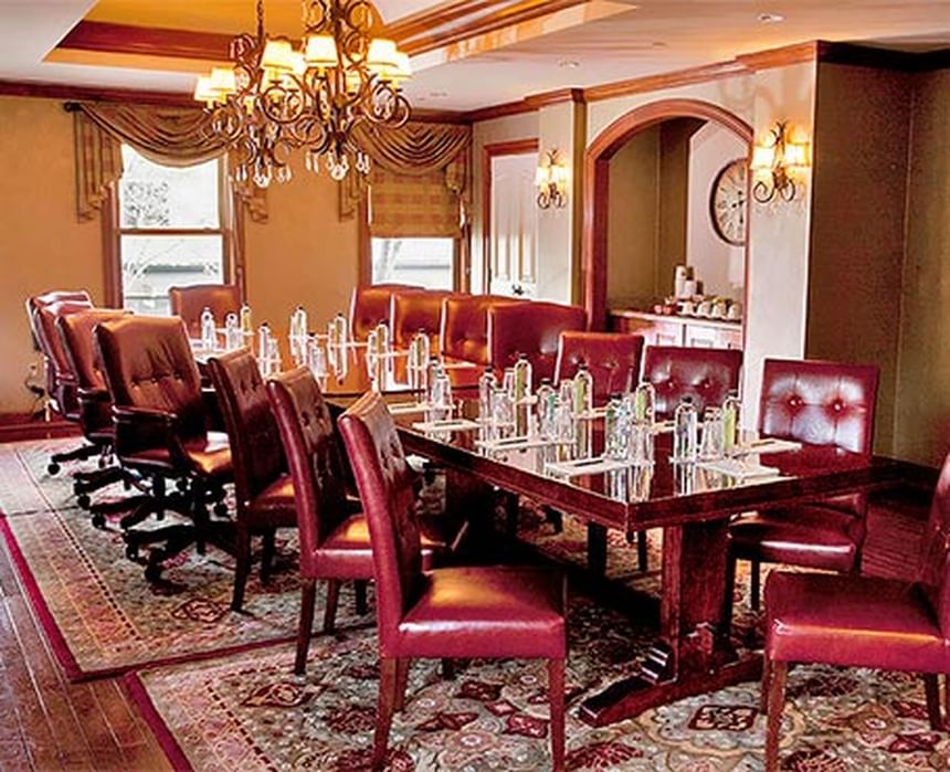Spacious, elegant conference room with a large wooden table surrounded by leather chairs at The Rose Hotel