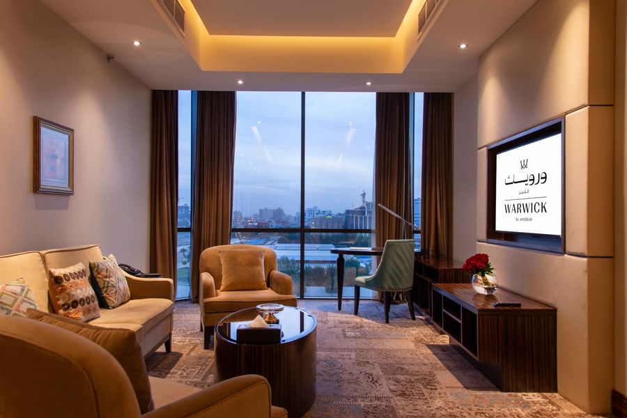 Ambassador Suite featuring a sofa by a TV and a desk under floor-to-ceiling windows at Warwick Al Khobar
