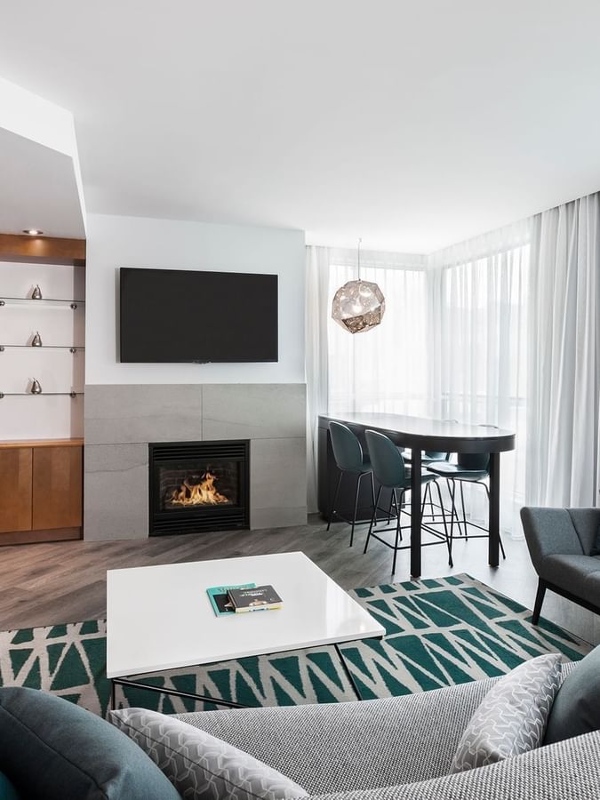 TV lounge with fireplace and dining area near the window in Penthouse Sainte-Catherine at Warwick Le Crystal Montreal