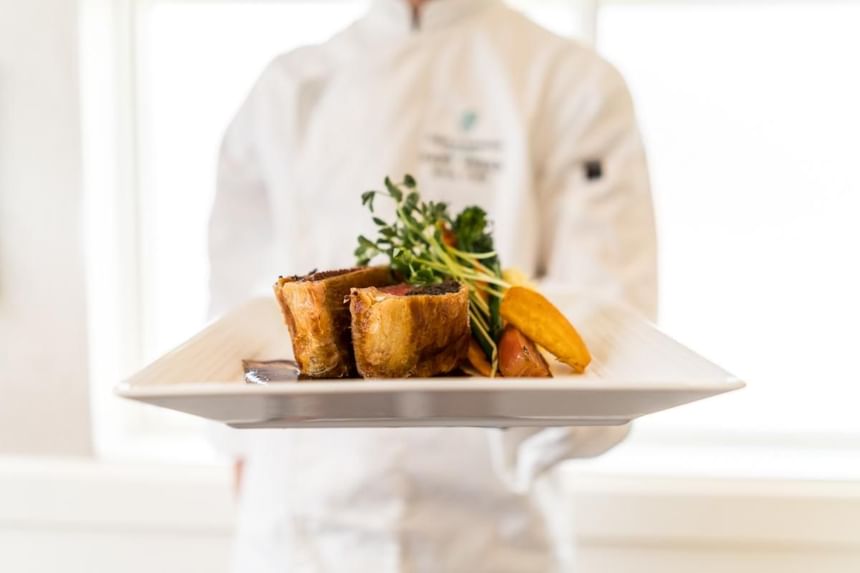 Chef presenting a plate of beef dish in Hardwood's Restaurant at Temple Gardens Hotel & Spa