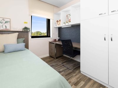 A cozy bedroom with bed, desk, chair, and window at UniLodge Darwin.