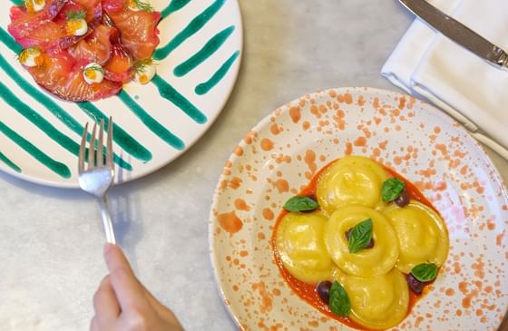 Marble table with seafood, pasta dishes, and a glass of drink served in Opera at Park Hyatt Saigon